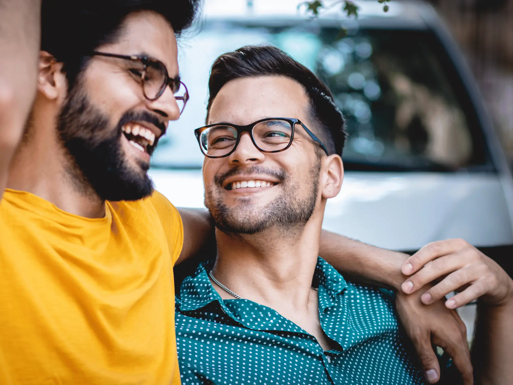 Two smiling men embracing outdoors